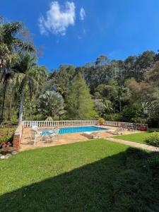a swimming pool with a table and chairs in a yard at um pedaço do paraíso in São Roque