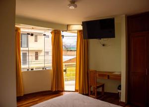 a bedroom with a bed and a desk and a window at Casa Qory in Cajamarca +19 photos