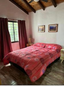 a bedroom with a red comforter on a bed at AlCarajo in Villa Yacanto
