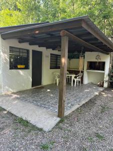 a small white house with a patio with a table at AlCarajo in Villa Yacanto