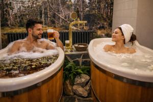 a man and a woman sitting in two tubs at REJVÍZ 1 Hotel & Spa in Rejvíz