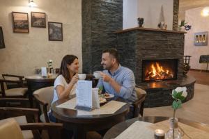 a man and woman sitting at a table in a restaurant with a fireplace at REJVÍZ 1 Hotel & Spa in Rejvíz +58 photos
