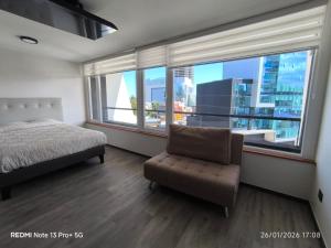 a bedroom with a bed and a chair and large windows at Departamento Piso 6 in Puerto Montt