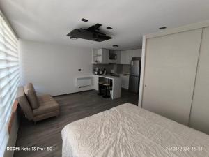 a bedroom with a bed and a chair and a kitchen at Departamento Piso 6 in Puerto Montt