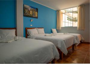 two beds in a room with a blue wall at Casa Qory in Cajamarca