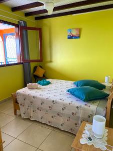 a bedroom with a bed and a yellow wall at Le Papillon Bleu in Bouillante