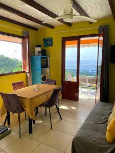 a dining room with a table and chairs and a balcony at Le Papillon Bleu in Bouillante