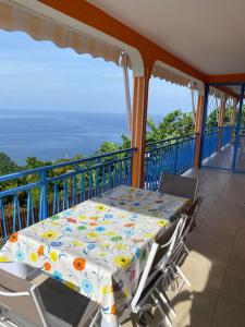 a table and chairs on a balcony with the ocean at Le Papillon Bleu in Bouillante