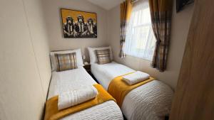 two twin beds in a small room with a window at Ingoldmells - Ingoldale Park Fantasy Island in Skegness