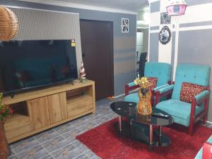 a living room with a tv and two chairs and a table at Master's Homestay in Suva