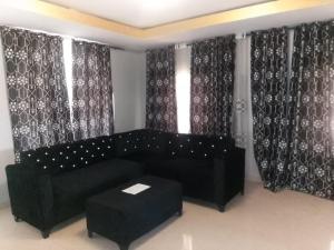 a living room with a black couch and curtains at Cutting Edge Guest House in Daranka +29 photos
