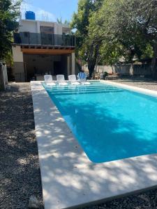 a swimming pool with chairs and a house at Casa Maria Bonita in Troncones