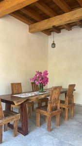 a wooden table with chairs and a vase with pink flowers at Casa Maria Bonita in Troncones