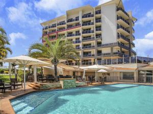 a hotel with a swimming pool in front of a building at Mantra Mackay in Mackay