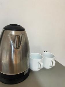 a coffee maker and two cups on a counter at Alona Chrisah Apartelle in Panglao Island