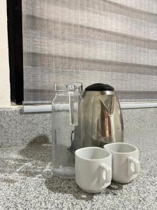a coffee pot and two cups on a counter at Alona Chrisah Apartelle in Panglao Island +22 photos