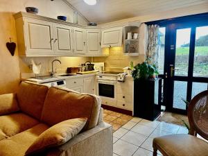 a living room with a couch and a kitchen at Smugglers Cottage converted Barn with Pool & Jacuzzi NR Lyme Regis in Whitchurch Canonicorum