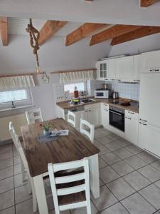 eine Küche mit einem Holztisch und weißen Schränken in der Unterkunft Haus Max in Dornum + 5 Fotos