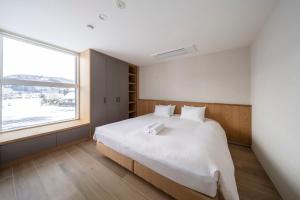 a bedroom with a large white bed with a window at Sakuraya in Hakuba