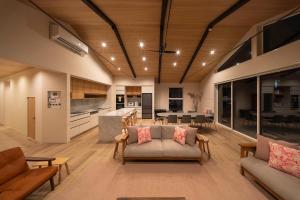 a living room with couches and a kitchen and a table at Sakuraya in Hakuba