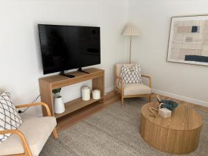 a living room with a flat screen tv and a chair at Beach Side Getaway Lighthouse Beach in East Ballina