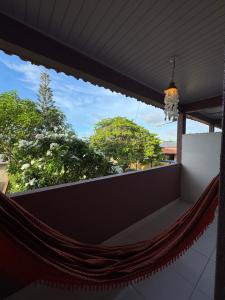 a hammock on a balcony with trees in the background at Professor Guest House in Santo Amaro
