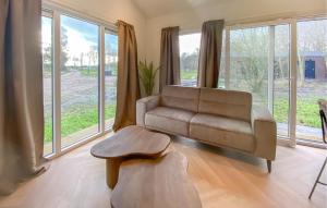 a living room with a couch and a table and windows at Sernets Recreatie Chalet 112 in Oud-Gastel