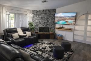 a living room with a leather couch and a flat screen tv at Casa Pueblo in Desert Hot Springs