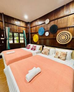 two beds in a room with wooden walls at Holy Villa in Kampot