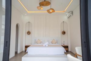 a bedroom with a white bed and two chairs at Lazura Serenite in Bangli