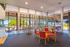 a dining room with tables and chairs and windows at The Beach Hotel Whyalla in Whyalla