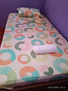 a bed with a polka dot bedsheet and two rolled towels at Posada Kevelin in Termales - agua caliente - nuqui