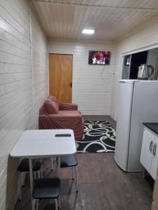 a small kitchen with a table and a refrigerator at Casa Contêiner Azul in Rosário do Sul