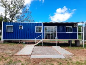 a blue tiny house sitting on top of a field at Casa Contêiner Azul in Rosário do Sul +2 photos