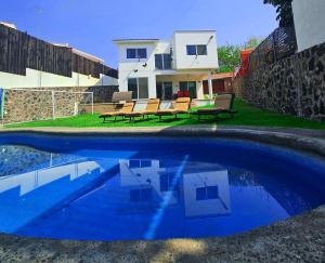a swimming pool with two benches and a house at Casa Adonai in Temixco