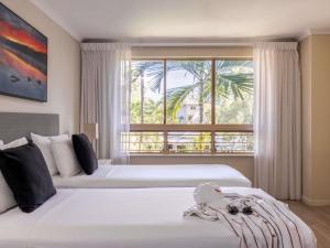 two beds in a hotel room with a window at Mantra Amphora in Palm Cove