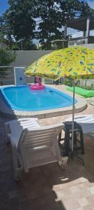 ein Sonnenschirm und ein Stuhl neben einem Schwimmbecken in der Unterkunft NuHostel in Conde