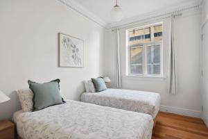 a white bedroom with two beds and a window at 53 Malop by Regional Escapes in Geelong