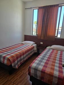 a hotel room with two beds and a window at Hostal Las Cruces II in Arica