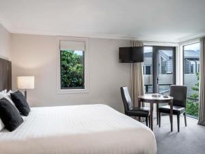 a hotel room with a bed and a table and chairs at Peppers Beacon in Queenstown