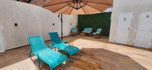 a patio with blue chairs and a table with an umbrella at Casa Abade - 4 Quartos - Excelente Localização in Itacaré