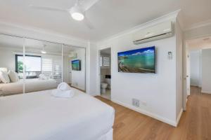 a white bedroom with a bed and a painting on the wall at Coral Sands 503 in Bargara +34 photos