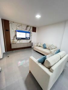 a living room with two couches and a flat screen tv at Pimentel Casa in Chiclayo +3 photos