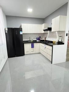 a kitchen with white cabinets and a black refrigerator at Pimentel Casa in Chiclayo