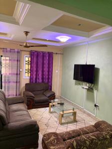 a living room with couches and a flat screen tv at Room 18 in Brusubi
