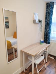 a table and mirror in a room with a bed at Cosy Single Room near Heathrow Airport in Hounslow