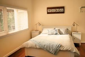 a bedroom with a bed with two lamps and a window at Banana Pancakes in Margaret River Town