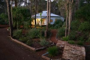 a small white house in the middle of a forest at Banana Pancakes in Margaret River Town