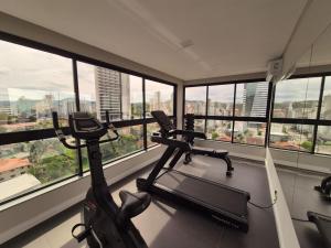 a gym with a treadmill in a room with windows at LINDO LOFT 350m Vila Germânica in Blumenau