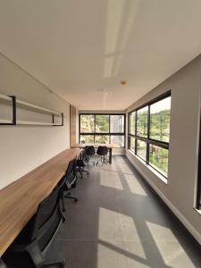 an office with chairs and a long desk and windows at LINDO LOFT 350m Vila Germânica in Blumenau